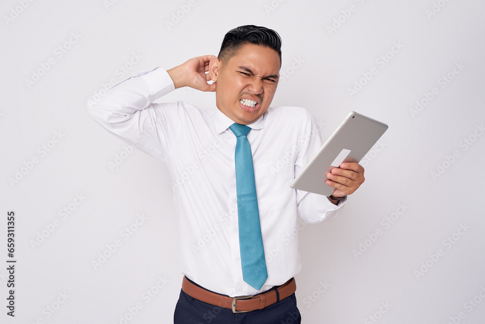 Confused young Asian man in formal wear holding a digital tablet and scratching his head isolated on white background Confused young Asian man in formal wear holding a digital tablet and scratching his head isolated on white background
