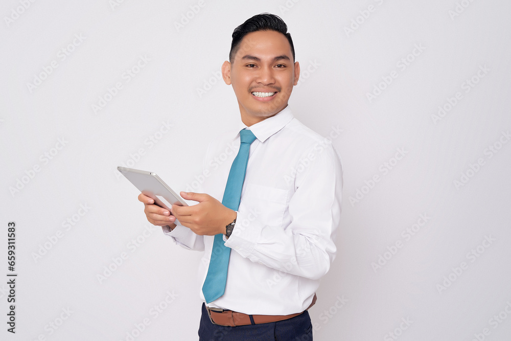 Portrait of smiling happy young Asian man in formal wear holding digital tablet and looking at the camera isolated on white background Portrait of smiling happy young Asian man in formal wear holding digital tablet and looking at the camera isolated on white background