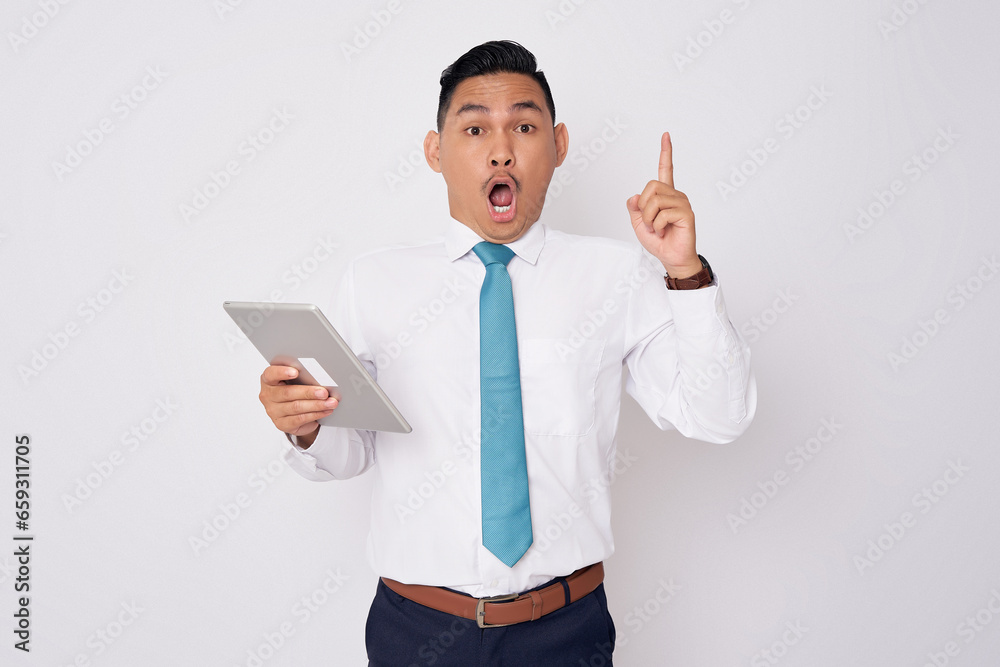 Portrait of excited young Asian man in formal wear pointing finger up getting idea after reading an article on tablet, solution on the problem in office isolated on white background Portrait of excited young Asian man in formal wear pointing finger up getting idea after reading an article on tablet, solution on the problem in office isolated on white background