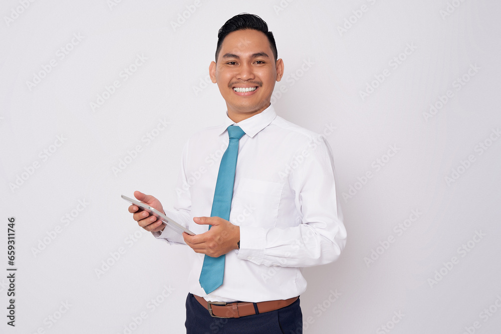 Portrait of smiling happy young Asian man in formal wear holding digital tablet and looking at the camera isolated on white background Portrait of smiling happy young Asian man in formal wear holding digital tablet and looking at the camera isolated on white background