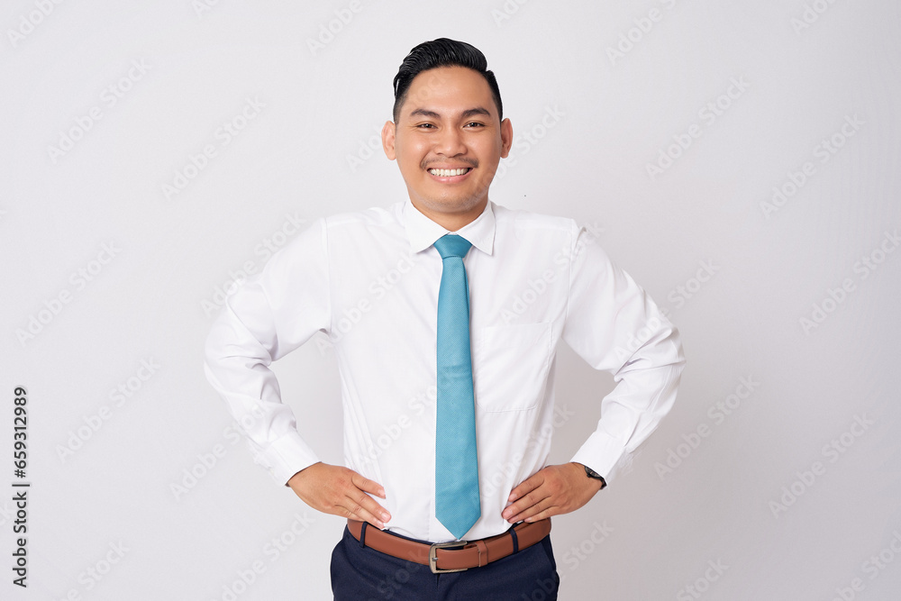 Portrait of a handsome young Asian man in formal wear standing confidently and looking at the camera while smiling happily and holding hands on waist isolated on white background Portrait of a handsome young Asian man in formal wear standing confidently and looking at the camera while smiling happily and holding hands on waist isolated on white background