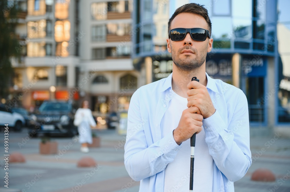 Young handsome blinded man walking with stick in town Young handsome blinded man walking with stick in town