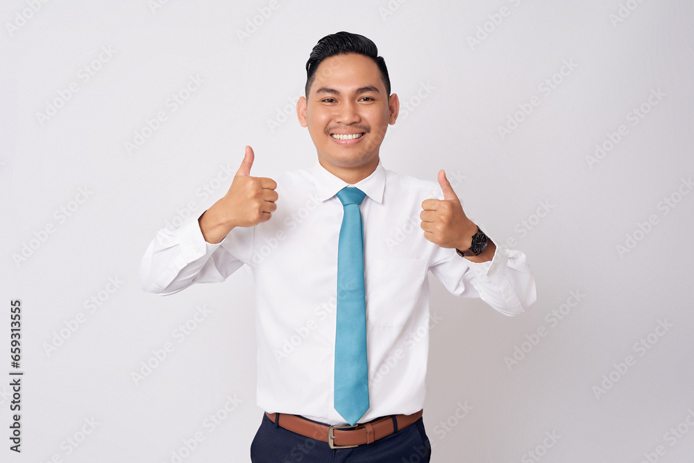 Portrait of a smiling happy successful young Asian man in formal wear standing confident while showing a thumbs up and looking at camera isolated on white background Portrait of a smiling happy successful young Asian man in formal wear standing confident while showing a thumbs up and looking at camera isolated on white background