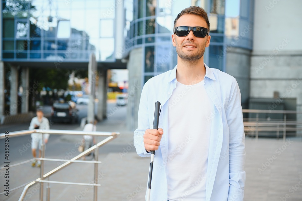 Portrait of a young, handsome blind man walking in the city. The concept of limited physical capabilities.