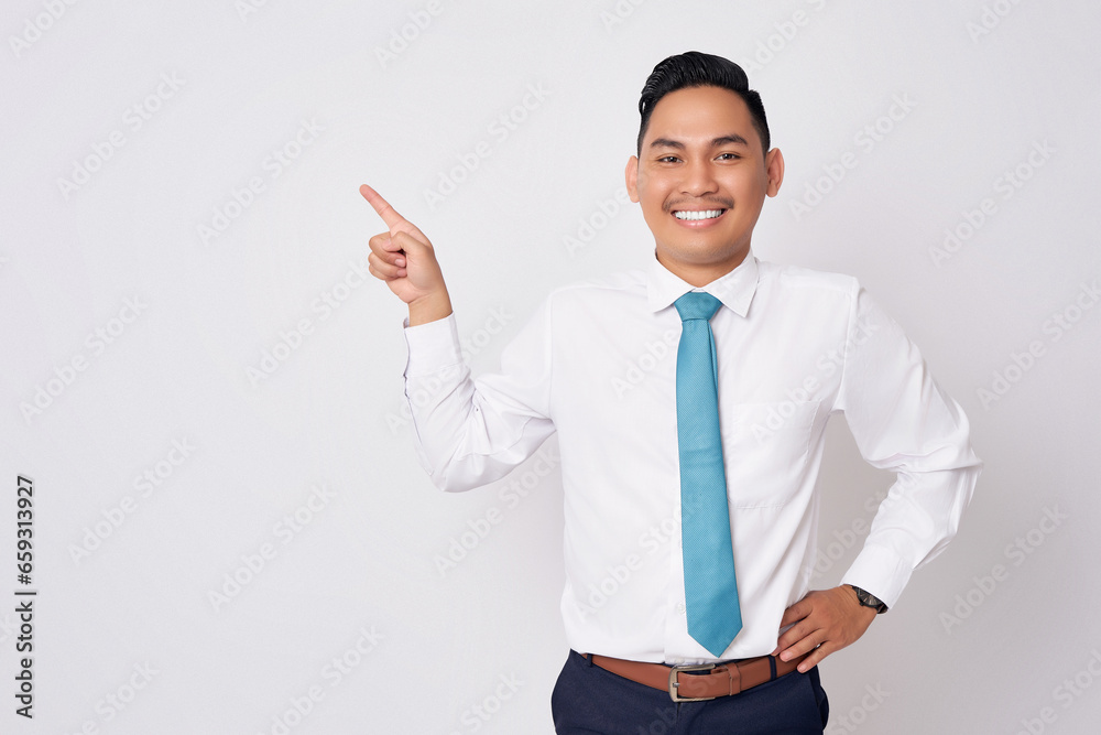 Portrait of a smiling happy young Asian man in formal wear standing pointing fingers aside at copy space for advertisement isolated on white background Portrait of a smiling happy young Asian man in formal wear standing pointing fingers aside at copy space for advertisement isolated on white background