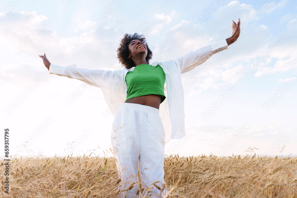 Carefree woman with arms outstretched standing in field Carefree woman with arms outstretched standing in field