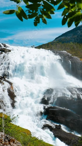 Kinsarvik, Hordaland, Norway. Waterfall Nyastolfossen In Hardangervidda Mountain Plateau. Nyastolsfossen in Spring Sunny Day. Famous Natural Norwegian Landmark Destination. Vertical Footage Video. photo