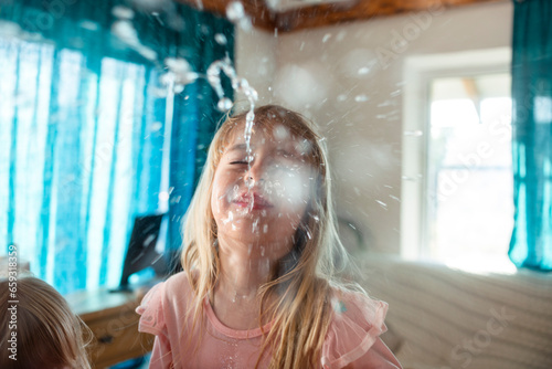 Blond girl laughing and spitting water from mouth at home photo