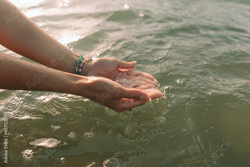 Woman holding water with cupped hands at beach