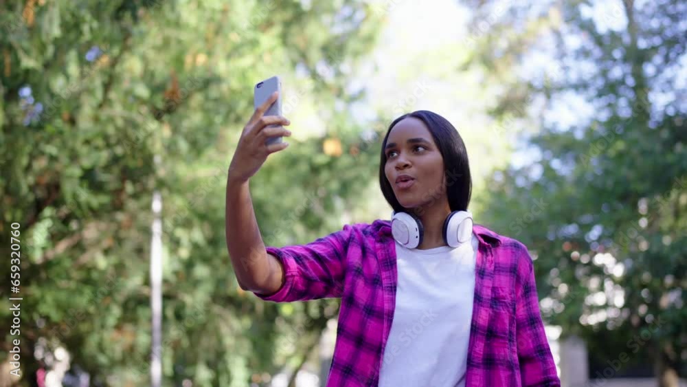 Black young woman live streaming outdoors. African American influencer recording video in a park. Black young woman live streaming outdoors. African American influencer recording video in a park.