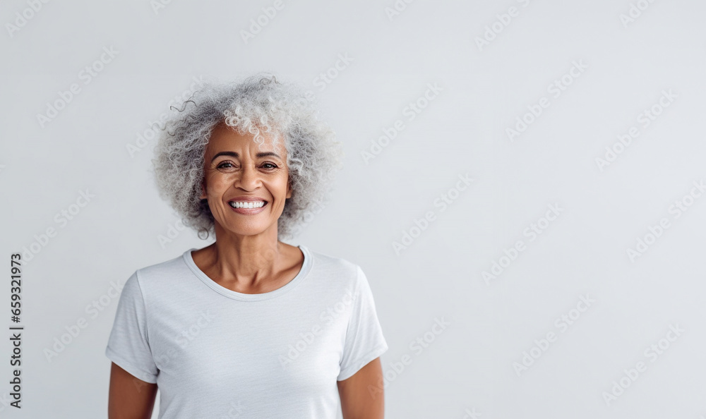 Portrait of smiling proud handsome african american senior woman standing against isolated white background. Wearing a white t-shirt copy space for advertisement or logo - obrazy, fototapety, plakaty 