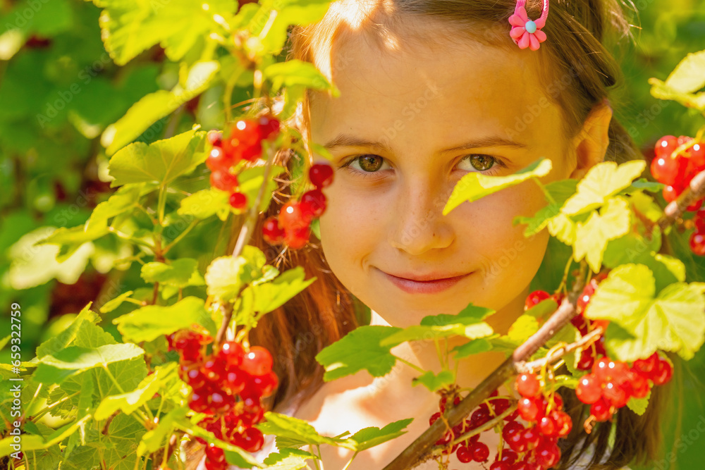 Naklejka premium Portrait of young girl with red currants berries on a green background