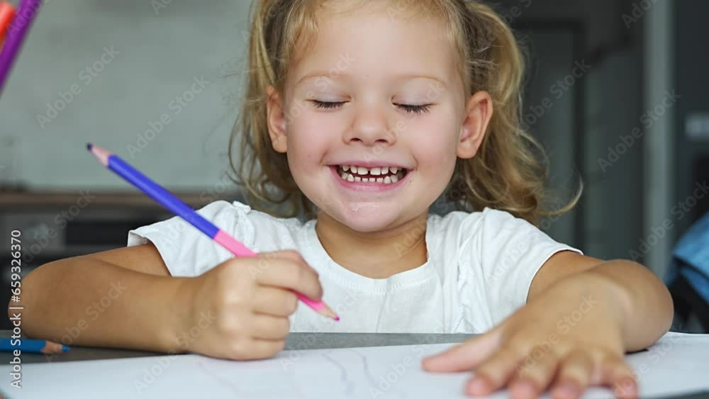Little girl draws with colored pencils in home. 