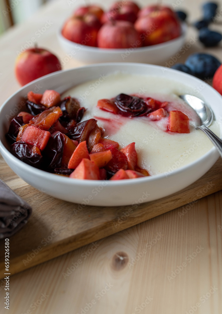 Semolina porridge with fresh cooked plums and apples on a plate. Lactose free