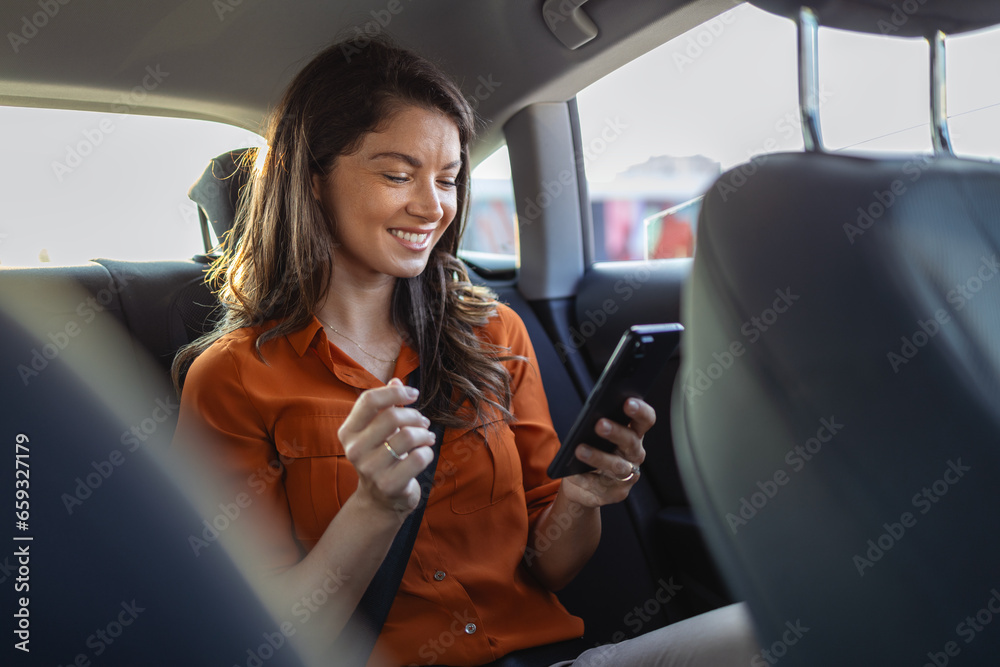 Successful young businesswoman in office clothes working using smart phone in sitting back seat of car in urban modern city in night. People occupational burnout syndrome concept.