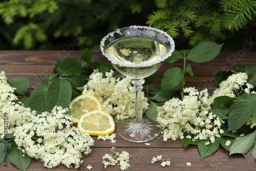 Glass of champagne with elderflower liqueur. Decorated with white elder flowers in natural background
