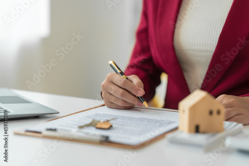 A young Asian real estate agent is reviewing documents and calculating interest rates to inform tenants of monthly installments before entering into contracts to buy or sell real estate. photo
