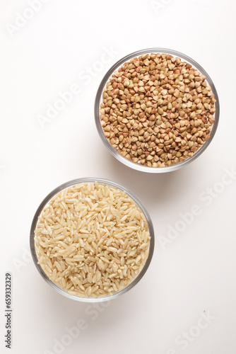 buckwheat and brown rice in glass bowl on white background shot from above