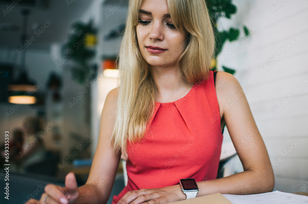 Focused young female employee using smartphone in cafe