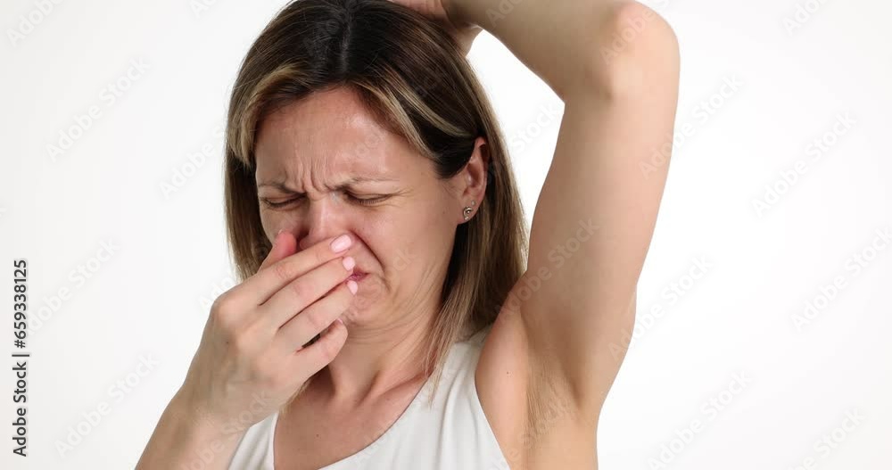 Woman sniffing unpleasant odor from armpit and covering nose with hand 4k movie slow motion. Sweat odor control concept Woman sniffing unpleasant odor from armpit and covering nose with hand 4k movie slow motion. Sweat odor control concept