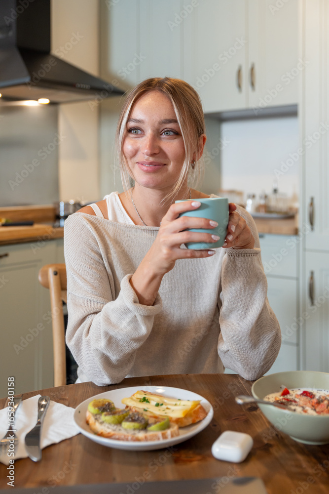 Caucasian female eating delicious healthy breakfast while sitting on kitchen