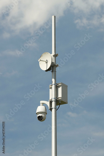 Surveillance system with an orange warning light located on a pole in the open. The threat of privacy and the protection of personal data. Security tracking on the streets of the city. Human mass
