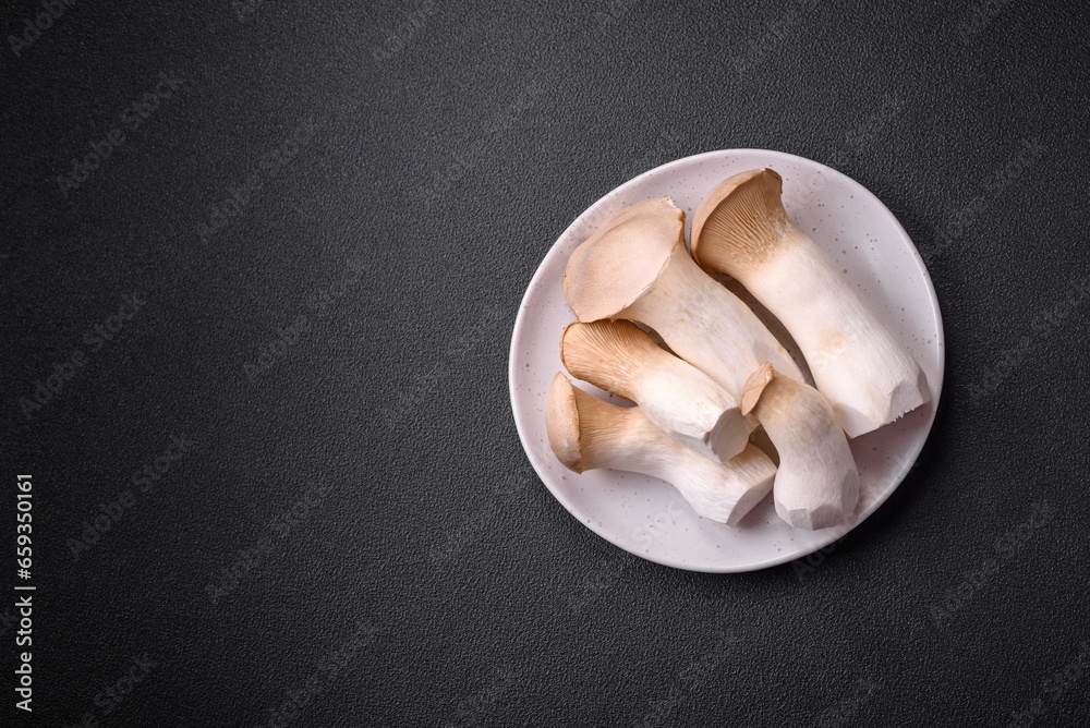 Pleurotus eryngii mushrooms on a dark concrete background Pleurotus eryngii mushrooms on a dark concrete background