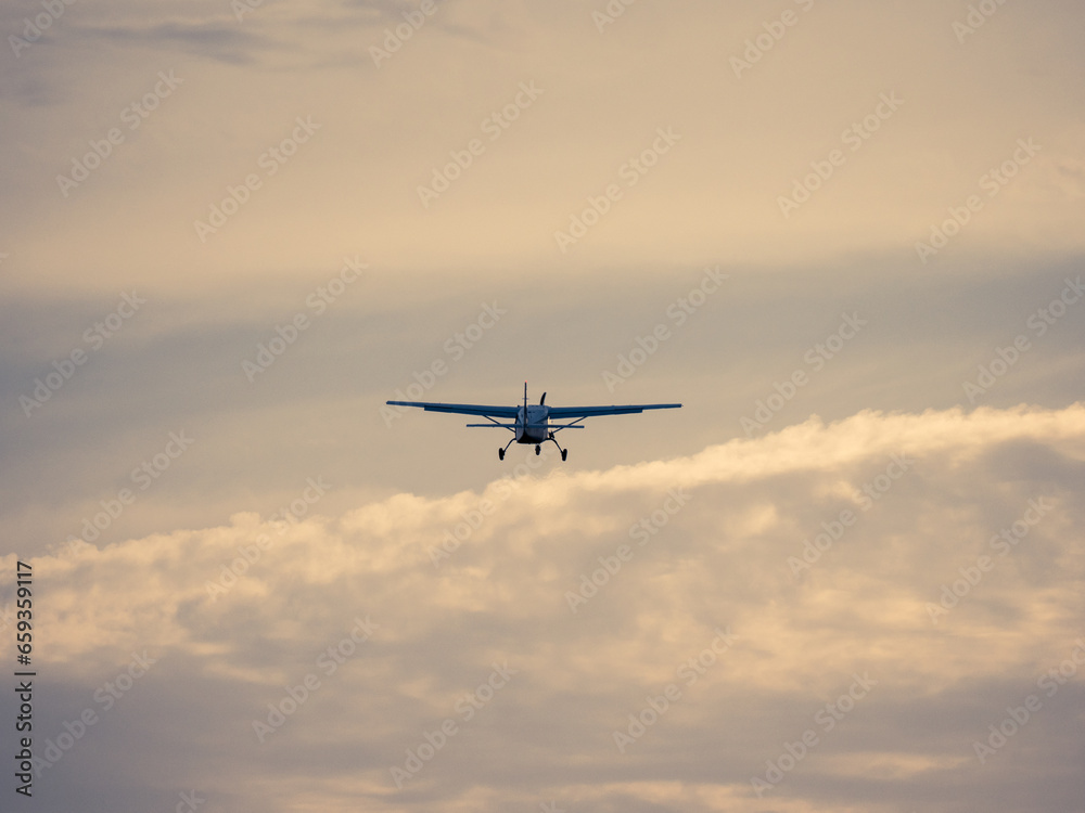 Man sieht ein kleines Flugzeug von hinten wie es in den ruhigen Abendhimmel aufsteigt und in die Ferne fliegt.