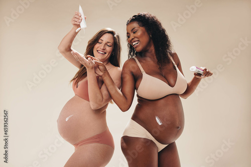 Pregnant moms having fun with applying stretch mark cream photo