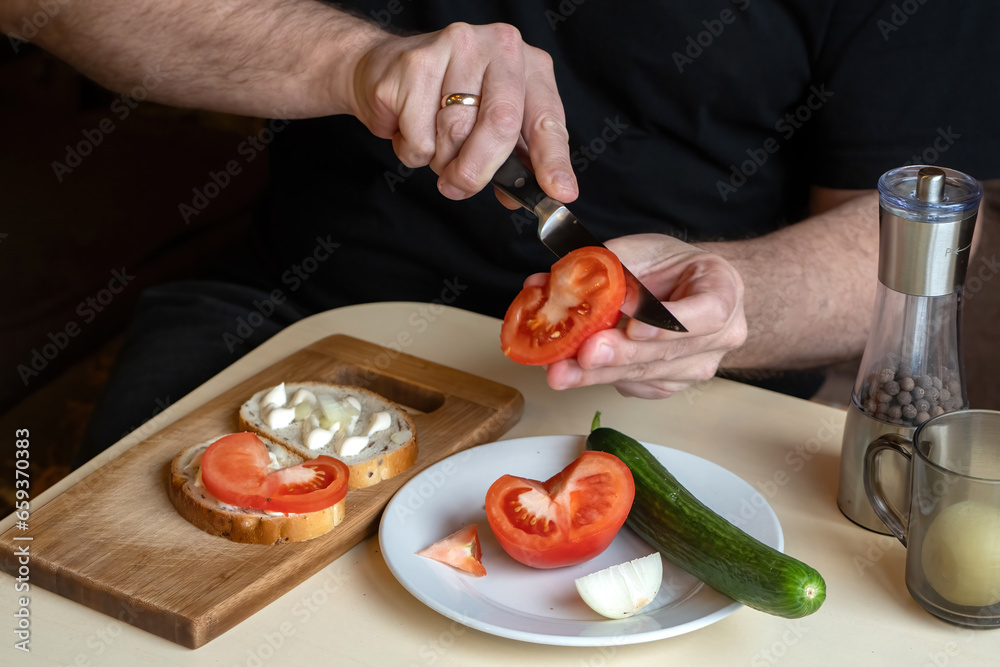 Man cuts tomato. Making sandwich with vegetables. Hands guy preparing snack. Bread with mayonnaise and tomatoes on cutting board. Man preparing sandwich. Snack recipe. Sandwich to satisfy your hunger