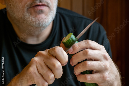 Man cuts cucumber. Guy is p...
