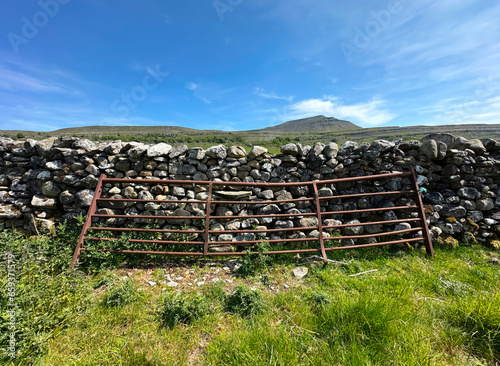 Old metal farmgate  leaning against a dry stone wall  high on the moors above  Ingleton  UK