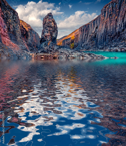 Huge basalt column reflected in Jokulsa A Bru river. Amazing summer view of Studlagil Canyon. Stunning morning landscape of Iceland, Europe. Beauty of nature concept background..