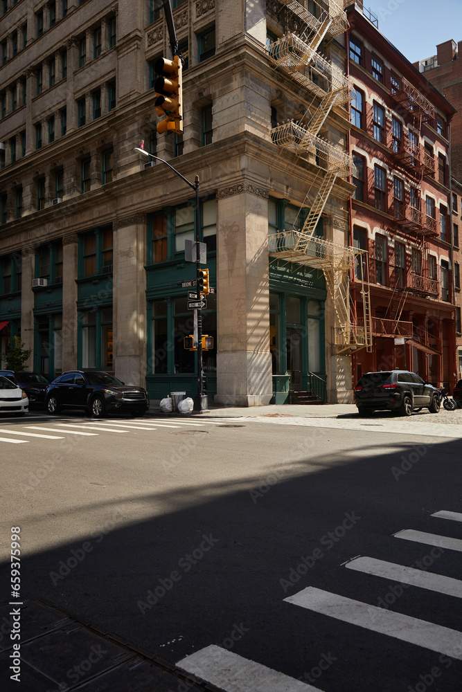 corner building with fire escape stairs and cars on crossroad on downtown street of new york city