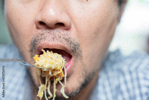 Close up of mouth eating fried noodle.