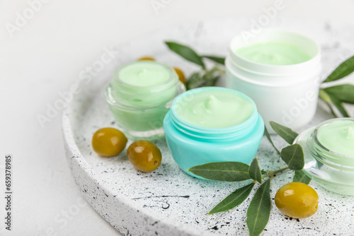 Jar of natural olive cream with olive oil extract on a texture background. Cosmetic tube. Moisturizing cosmetic cream for skin. Body care. Beauty concept. Copy space. Flat lay. Hand cream.