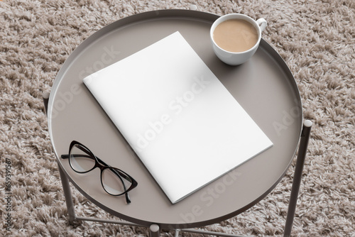 Magazine mockup with a cup of coffee on the beige table.