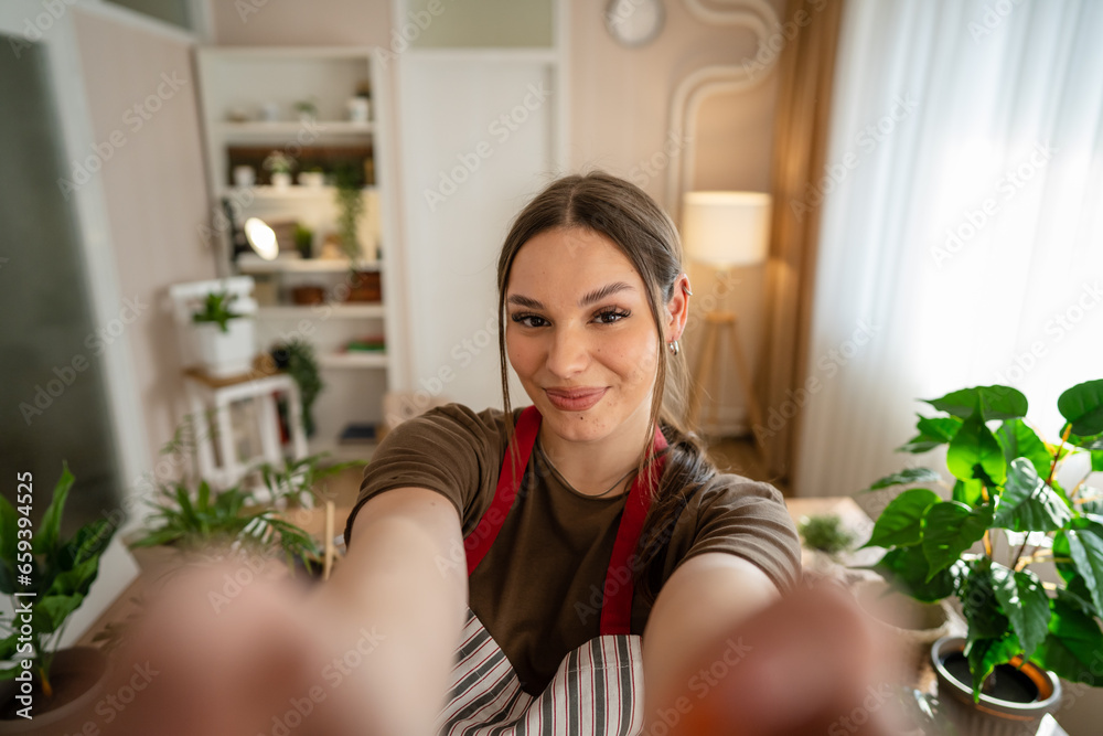 One woman young caucasian female stand at home hold flower plants pot One woman young caucasian female stand at home hold flower plants pot