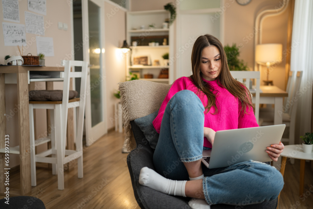 One young woman use laptop computer at home while sit comfortable One young woman use laptop computer at home while sit comfortable