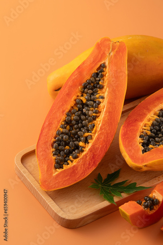 Fresh tropical cut papaya fruit over orange table background.