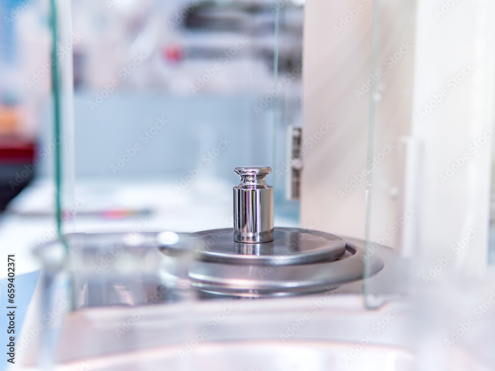 Analytical balance in a laboratory with a metal weight. Concept of laboratory balance calibration. Analytical balance in a laboratory with a metal weight. Concept of laboratory balance calibration.