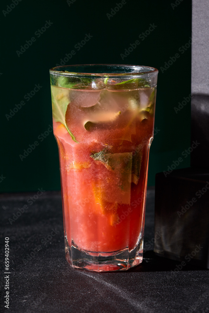Strawberry-basil lemonade in a glass, a delightful fusion of sweet and herby flavors against a stark black backdrop