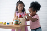 Two girls of different nationalities play with educational toys together, group study concept