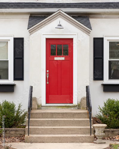 Canvas Print A red front door detail on a white home with concrete steps and iron railings leading up to the door