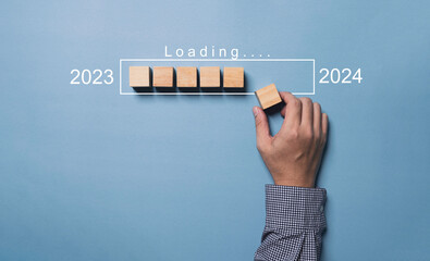 Businessman hand assemble wooden block cube for assemble download technology bar to countdown from 2023 to 2024 year , Preparation happy new year and merry Christmas concept.