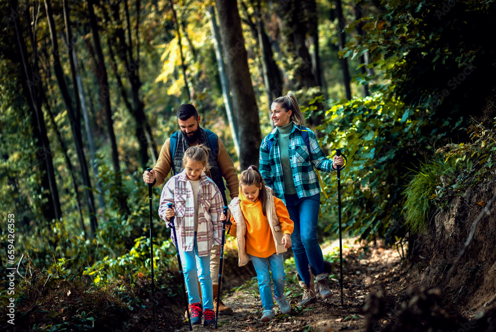 Smiling family of four enjoying hiking in trough forest.