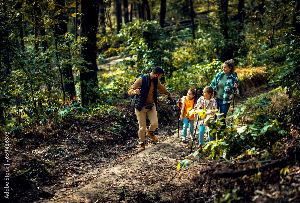 Naklejka premium Smiling family of four enjoying hiking in trough forest.