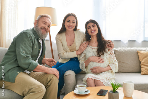 joyous father paying visit to his pregnant daughter and her partner, looking at camera, ivf concept