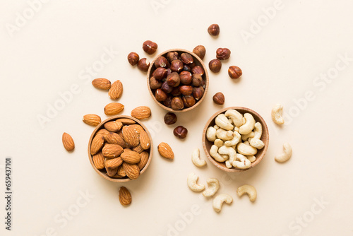 Assortment of nuts in wooden bowl on colored table. Cashew, hazelnuts, walnuts, almonds. Mix of nuts Top view with copy space © sosiukin