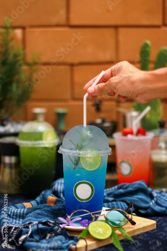 Blue Hawaii, iced lemon lime soda, a cooling drink placed on a classic wooden table decorated with lemon petals.